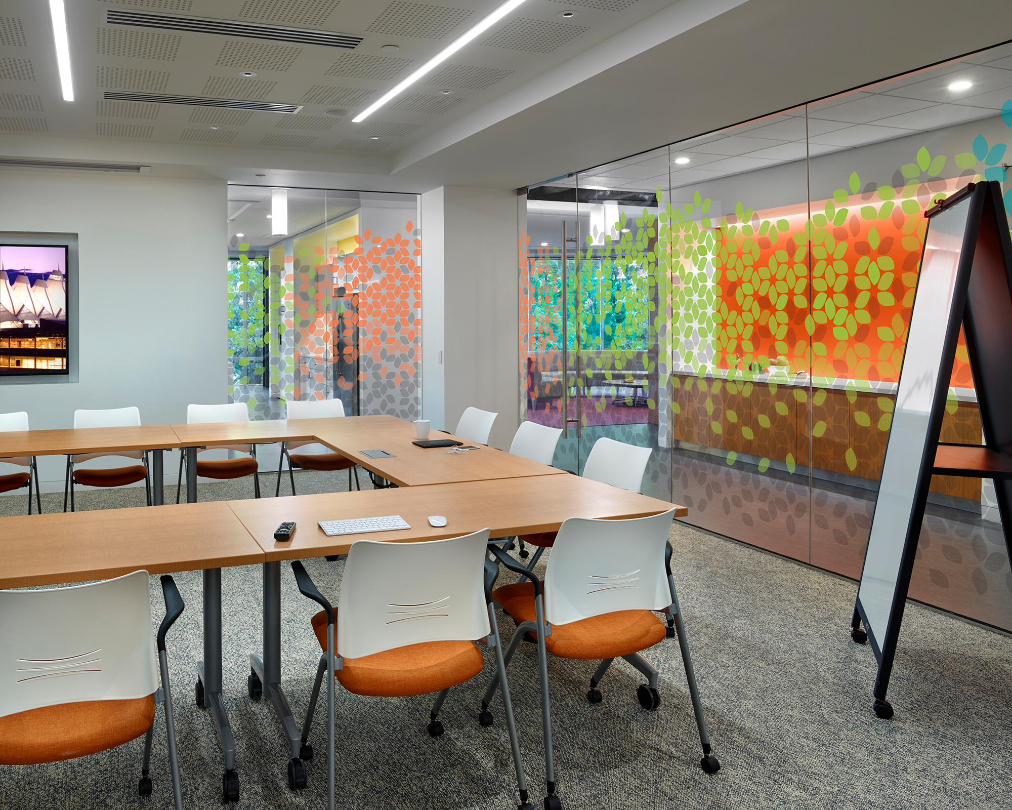 A wooden conference room table with chairs and glass walls. 